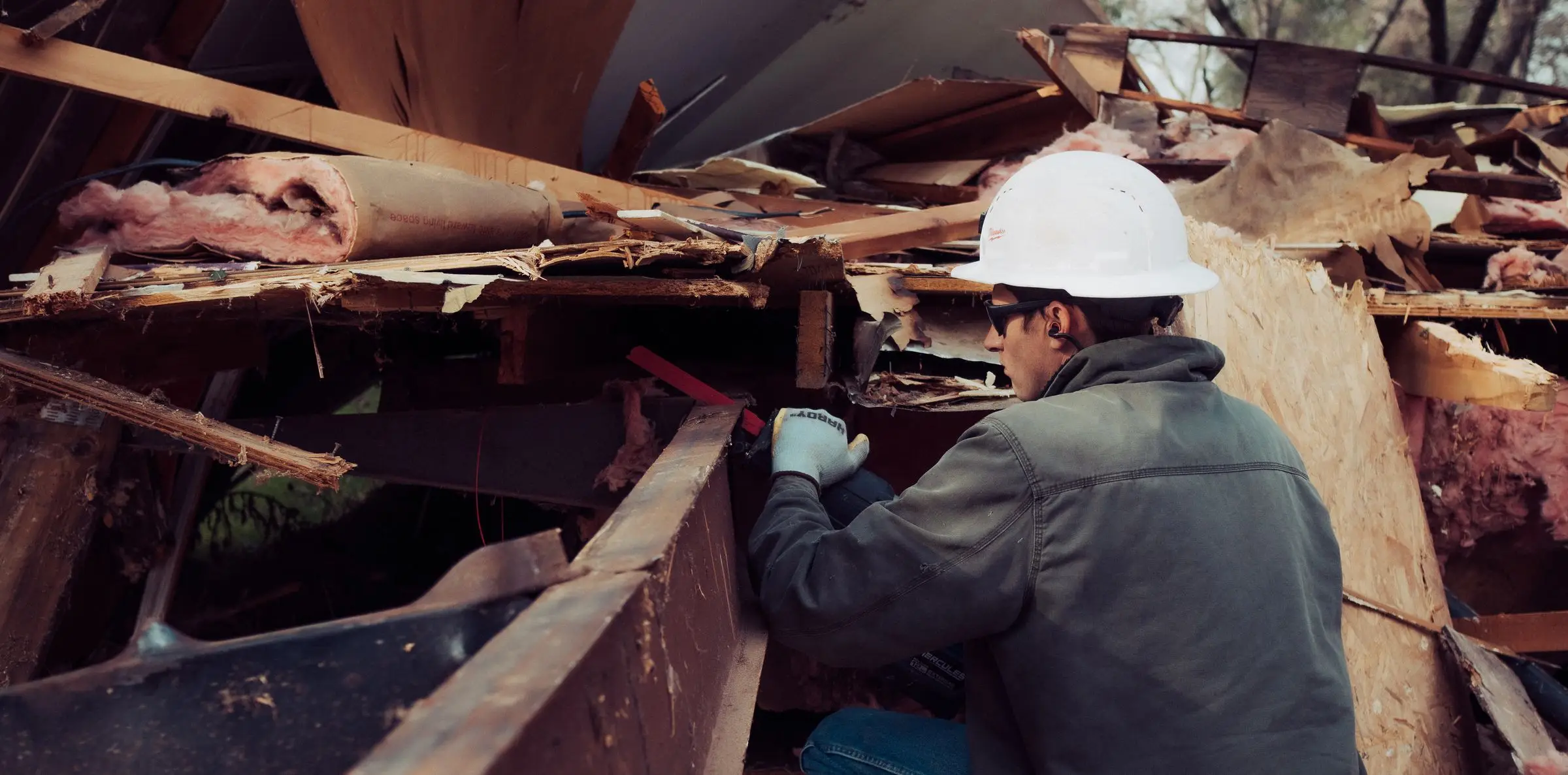 Crew member in a hard hat clearing debris by hand