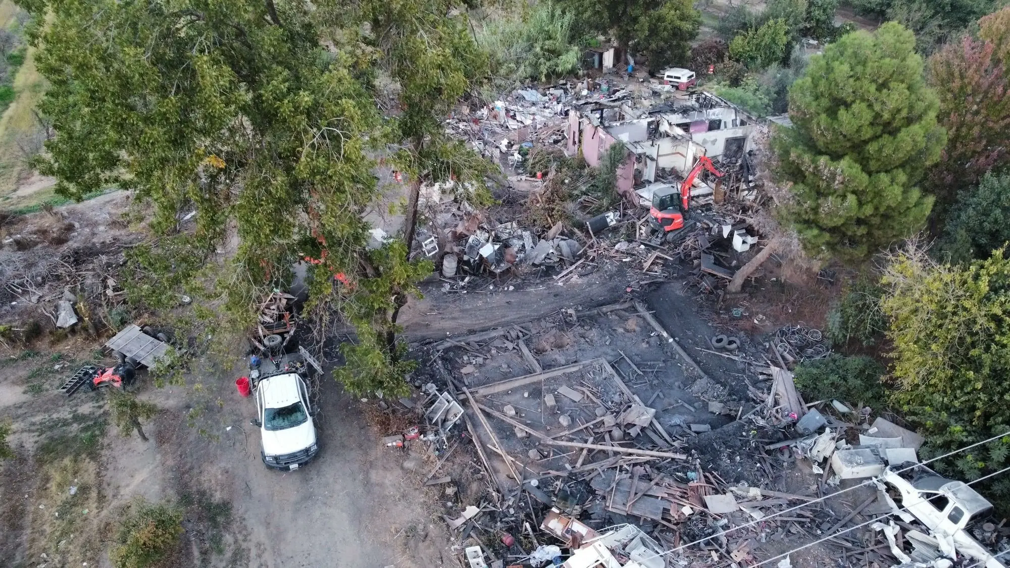 Aerial view of an excavator clearing debris from a burned property