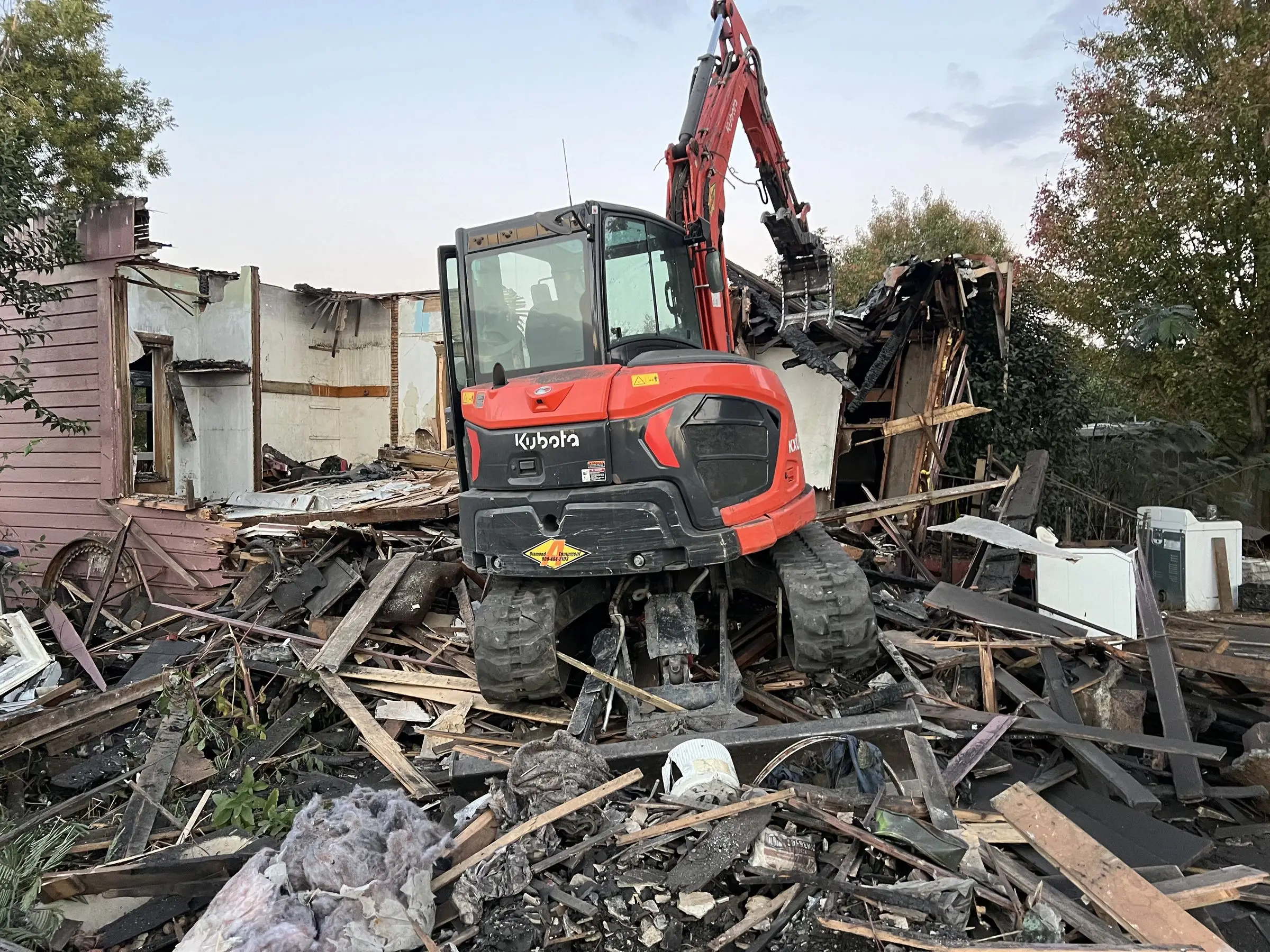 Kubota excavator on a pile of house demolition debris