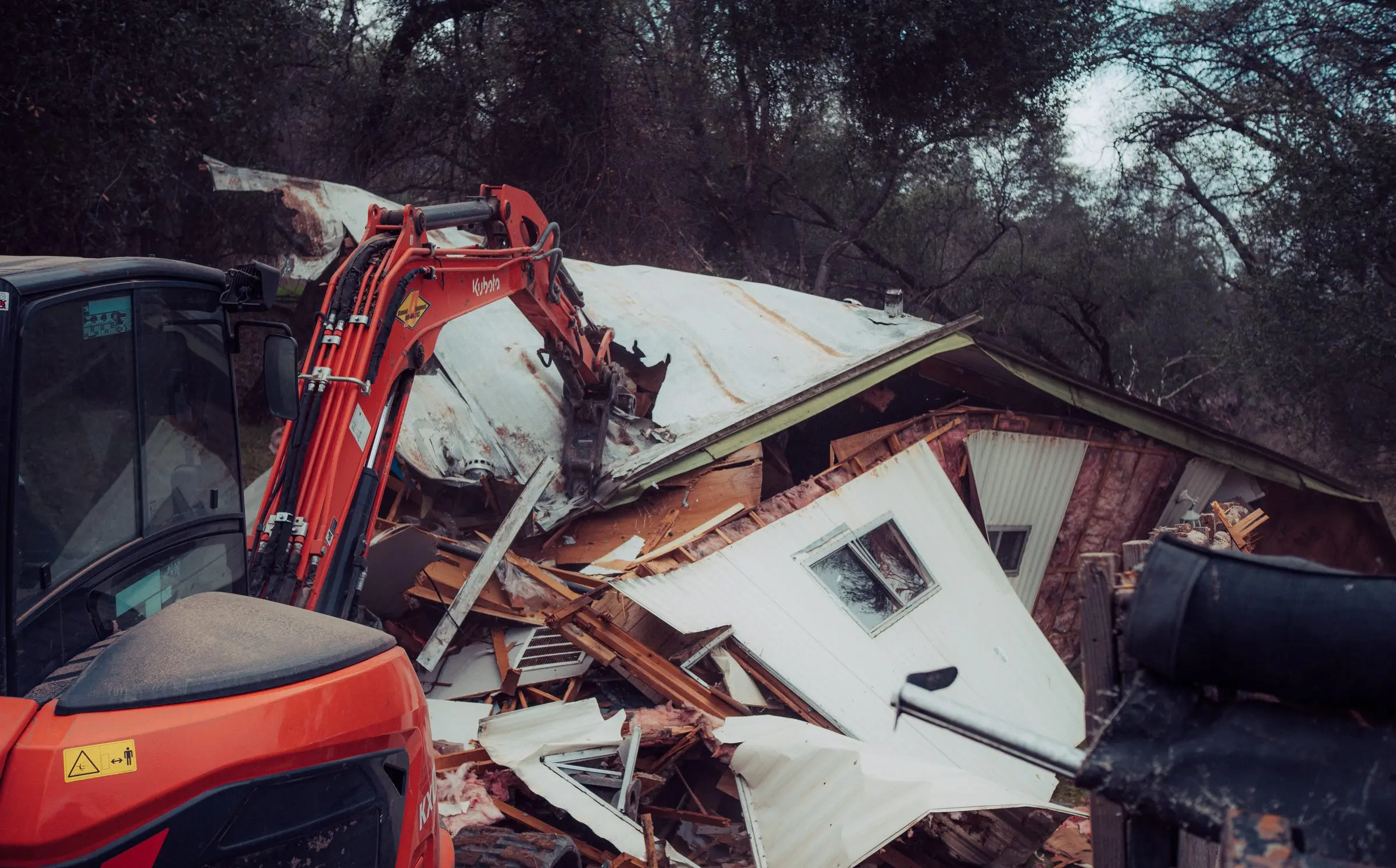 Excavator pulling the roof off a mobile home